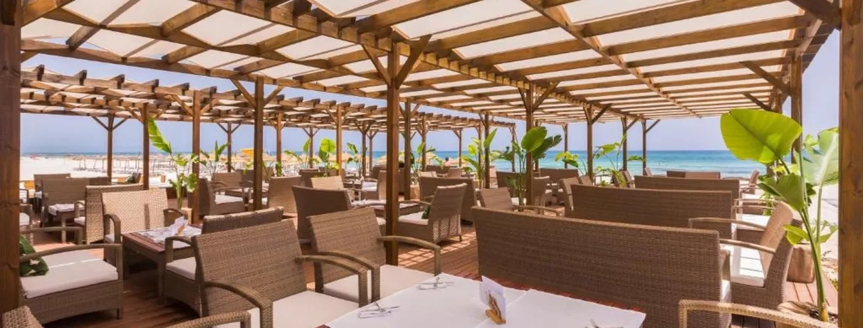 Restaurant en bord de mer, terrasse ombragée avec mobilier en rotin élégant