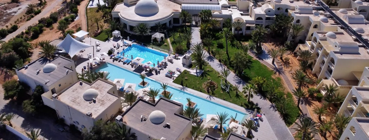 Vue aérienne des jardins et piscines turquoise de l'hôtel César Thalasso, destination de voyage à Djerba.