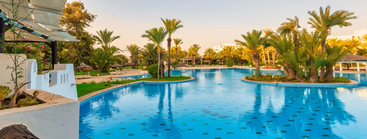 Espace de baignade luxueux avec îlots de palmiers au Djerba Resort, destination de vacances en Tunisie.