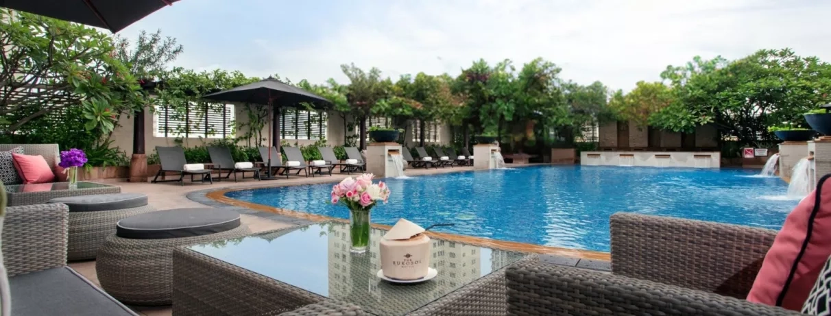 Une terrasse avec des fauteuils offrant une vue directe sur la piscine.