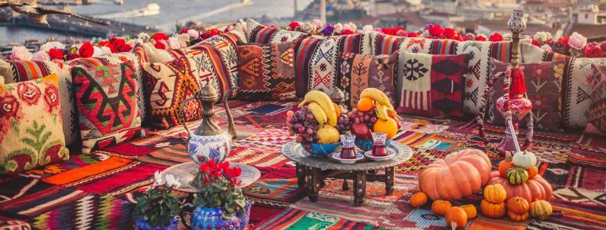 Un coin salon oriental coloré en terrasse, avec coussins traditionnels, thé et fruits.