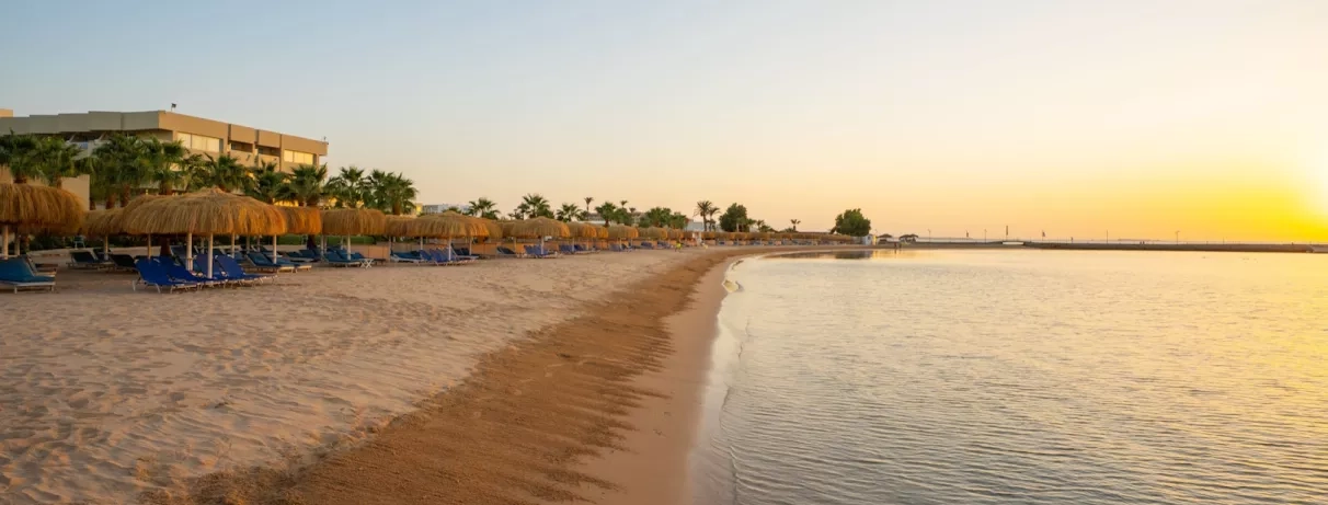 parasols, transats, au bord de la mer, sable fin, yacht sur le quai, coucher de soleil