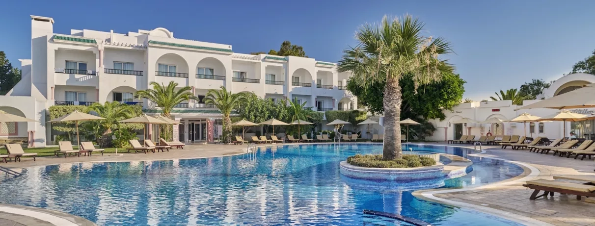 bâtiment de l'hôtel avec piscine extérieure et palmier au centre 