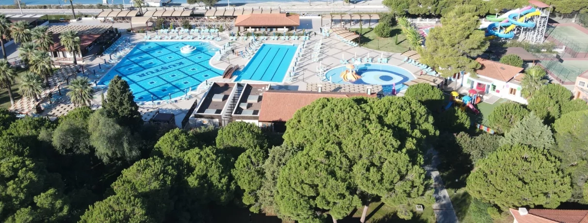 Un complexe de loisirs avec plusieurs piscines entourées de terrasses et de végétation.