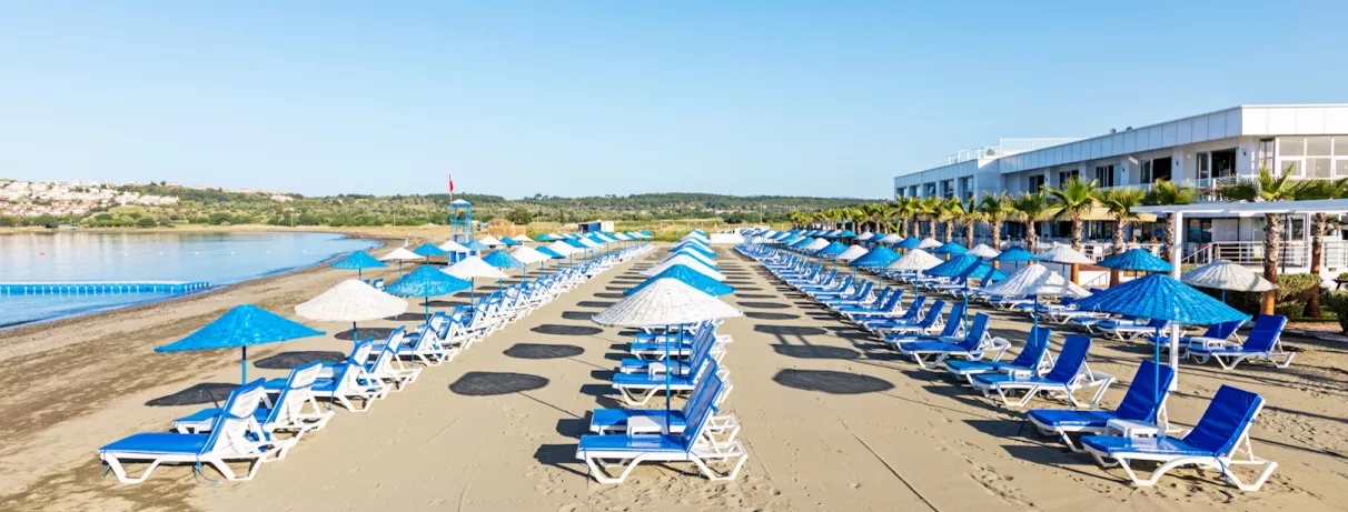 Des rangées de parasols bleus et blancs s'étendant vers l'horizon le long du rivage.