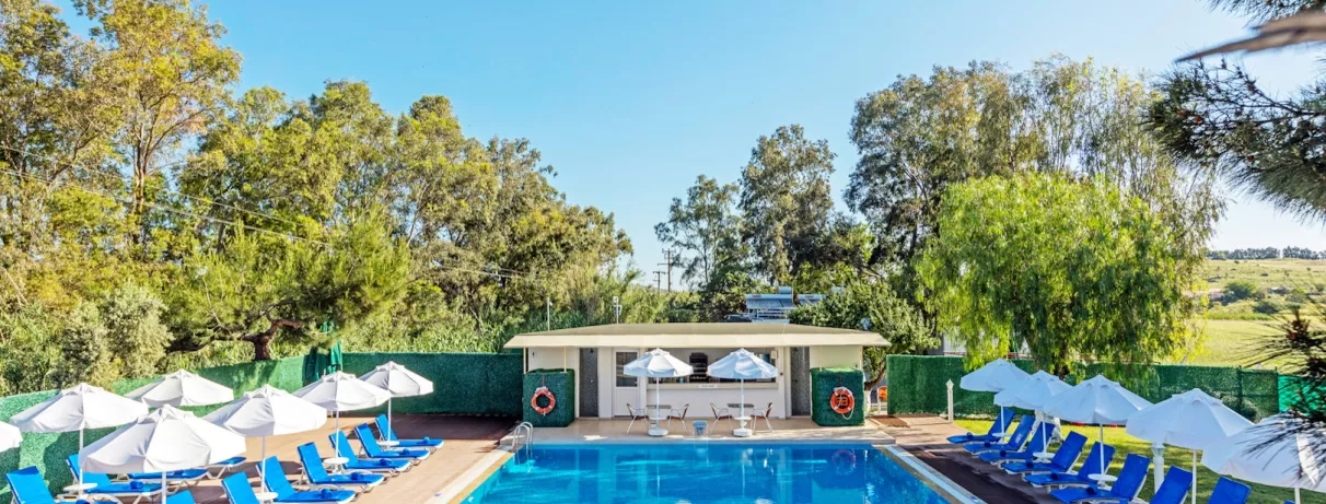 Un piscine entouré de parasols blancs et de transats, niché au cœur de la végétation.