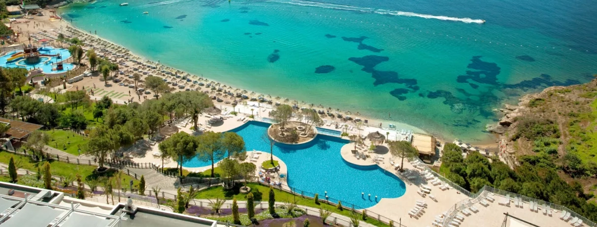 Une vue aérienne du complexe hôtelier bordant une eau turquoise cristalline.