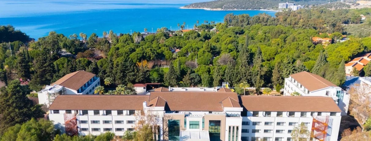 Une vue aérienne montrant le complexe hôtelier niché au cœur d'une forêt, avec la mer.