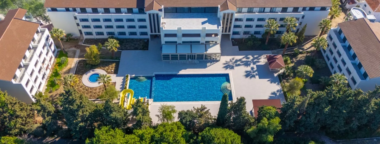 Une vue plongeante centrée sur l'espace baignade et les bâtiments de l'hôtel.