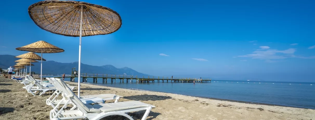Un moment de détente sur la plage avec des transats et des parasols en paille.