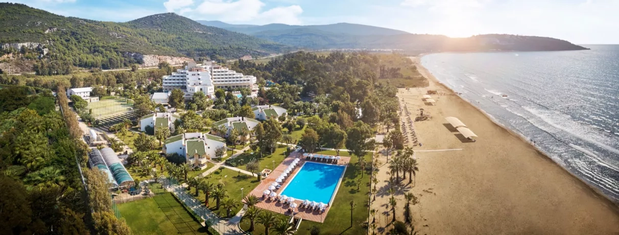 Un panorama spectaculaire avec un complexe hôtelier entre montagnes et plage.