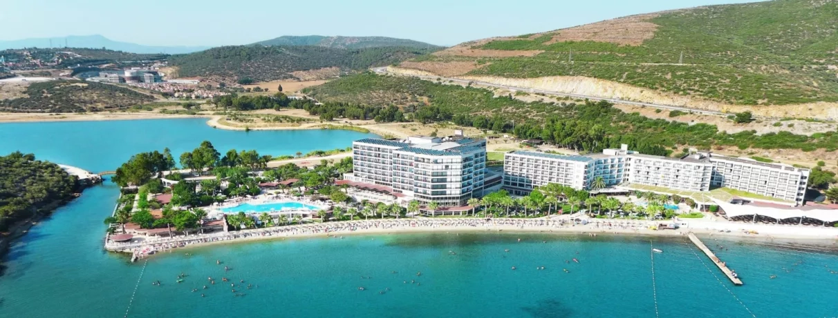 Une vue aérienne montrant le complexe hôtelier niché entre une colline et la mer.