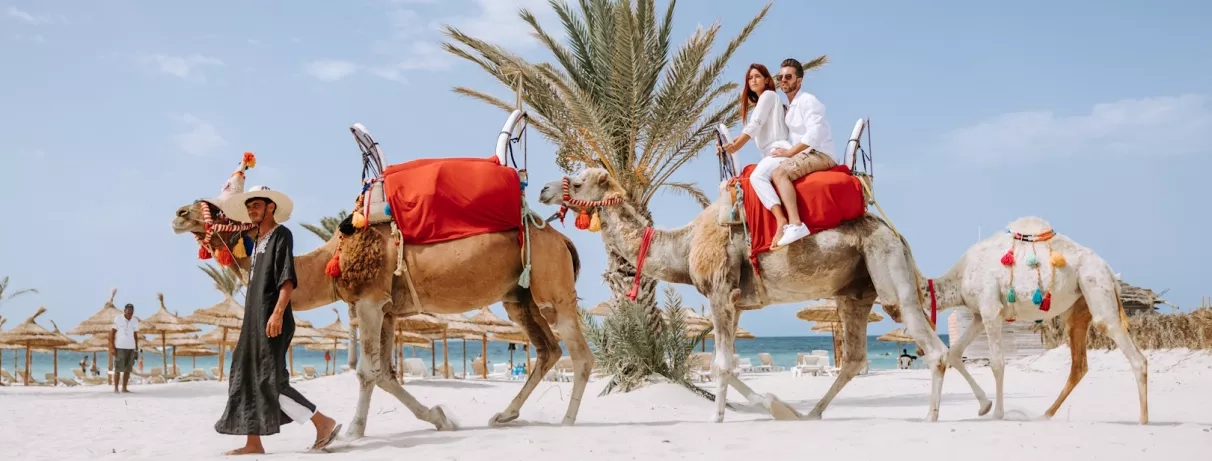 Couple à dos de chameau lors d'une balade sur la plage de sable blanc du Djerba Golf.