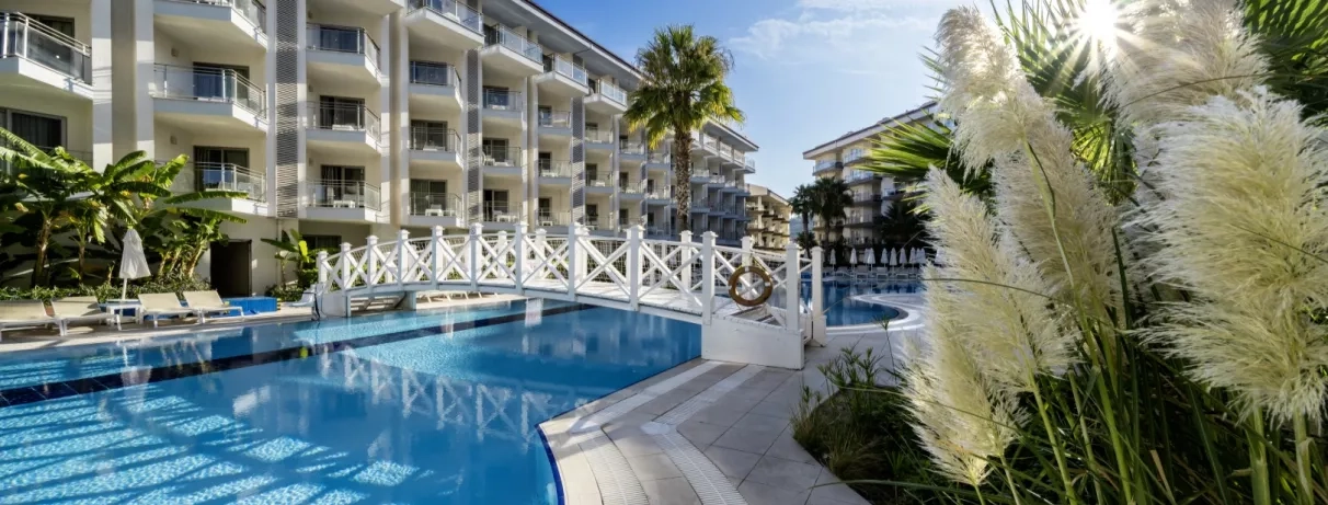 Un élégant pont blanc enjambant une piscine, entouré de palmiers et de végétation tropicale.