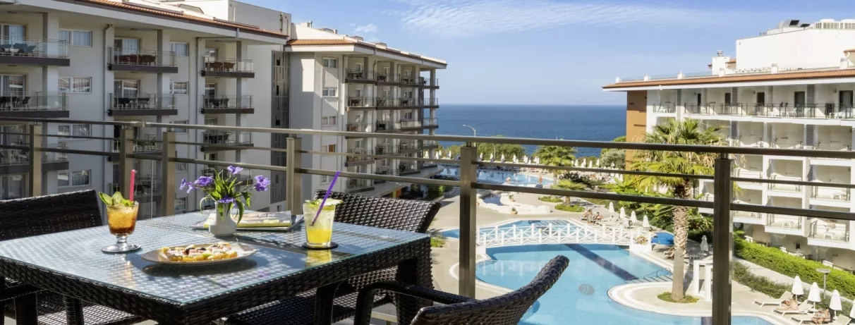 Une terrasse ensoleillée offrant une vue plongeante sur les piscines et la mer.