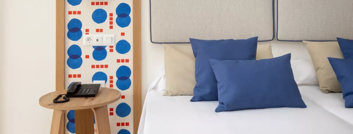 Une chambre avec le détail des coussins bleus marines sur le lit et de la table de chevet. 