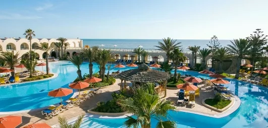Vue panoramique sur les piscines extérieures et la mer Méditerranée au complexe hôtelier Djerba Beach.