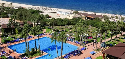 Vue aérienne complexe hôtelier Sahara Beach Monastir avec grande piscine, jardins et plage de sable fin.
