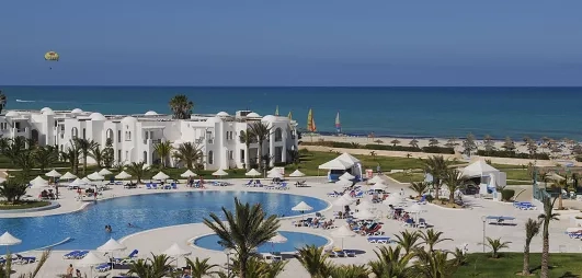 Jardin luxuriant et piscines du complexe hôtelier en bord de mer Méditerranée pour des vacances en Tunisie.