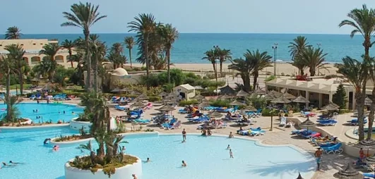 Grande piscine lagon et palmiers à l'hôtel Zephir Djerba en bord de mer Méditerranée, Tunisie.