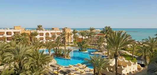 Vue panoramique sur les jardins, la piscine bleue et la plage méditerranéenne du complexe touristique Safira Palms Djerba.