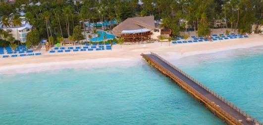Plage avec ponton, sable, eau claire, transats bleus, plusieurs piscines, végétation