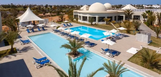 Bassins de baignade et terrasses avec parasols sous le ciel bleu de Djerba en Tunisie.
