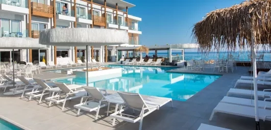 piscine avec transats, parasols, pieds dans l'eau, hôtel avec balcons couleur bois