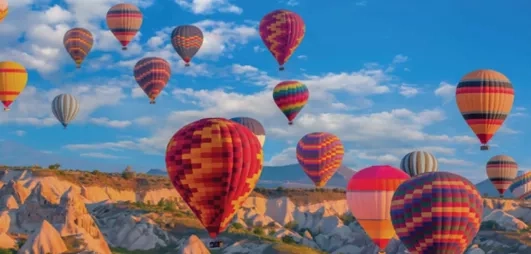 Un ciel remplis de montgolfières survolant les formations rocheuses uniques de la région.