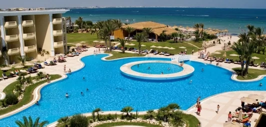 Grande piscine extérieure bleue et jardins palmiers de l'hôtel Royal Thalassa à Monastir, Tunisie.