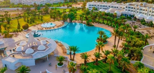 Vue aérienne panoramique du Royal Garden Palace à Djerba, incluant piscine lagon, jardins et architecture tunisienne.