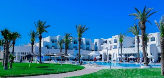 Grande piscine extérieure entourée de palmiers et architecture blanche typique de l'hôtel Al Jazira à Djerba.