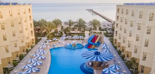 vue de haut de l'hôtel avec le bâtiment et la piscine au milieu, toboggans, transats, soleil, 