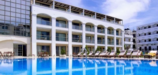 bâtiment de l'hôtel avec les terrasses des chambres donnant sur la piscine extérieur entourée de transats  