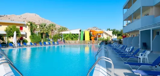 vue d'ensemble piscine aquapark 3 toboggans vert jaune orange montagne transats bleus bâtiments de l'hôtel
