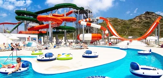 Grand aquapark avec piscine, transats, sous le soleil, montagne, personnes dans des bouées