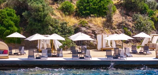 piscine avec des transats, des parasols et des lits