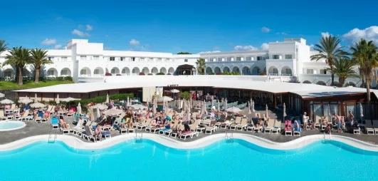 Une vue panoramique d'une grande piscine, bordée de transats devant l'hôtel.