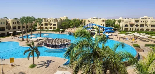 Grande piscine lagon, toboggans aquatiques et palmiers au Mondi Club Stella Gardens Resort & Spa, Hurghada Égypte.