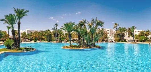 Vaste piscine turquoise entourée de palmiers et d'architecture traditionnelle à Djerba pour des vacances de détente.