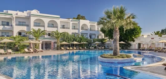 bâtiment de l'hôtel avec piscine extérieure et palmier au centre 