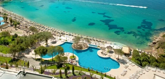 Une vue aérienne du complexe hôtelier bordant une eau turquoise cristalline.