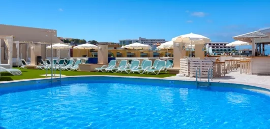 Une piscine d'un bleu éclatant entourée de parasols blancs et de bâtiments élégants sous un ciel radieux.