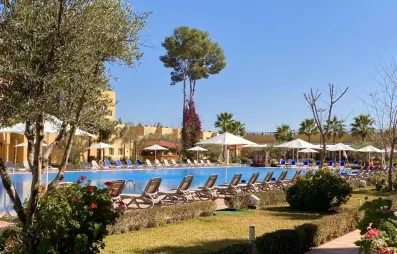 vue générale sur la partie piscine de l'hôtel avec les transats tout autour et une partie jardin