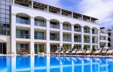 bâtiment de l'hôtel avec les terrasses des chambres donnant sur la piscine extérieur entourée de transats  