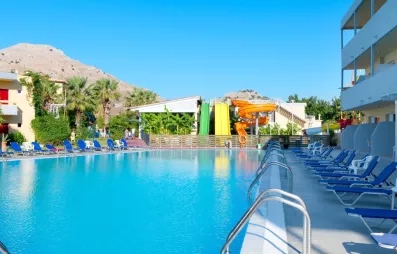vue d'ensemble piscine aquapark 3 toboggans vert jaune orange montagne transats bleus bâtiments de l'hôtel