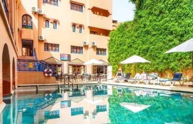 Une vue sur la piscine de l'hôtel, encadrée par un bâtiment moderne aux murs ocre et un grand mur végétal.