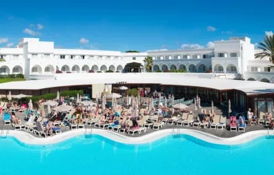 Une vue panoramique d'une grande piscine, bordée de transats devant l'hôtel.