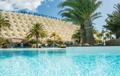 Vue sur la façade du bâtiment et la végétation tropicale qui entoure le bassin.