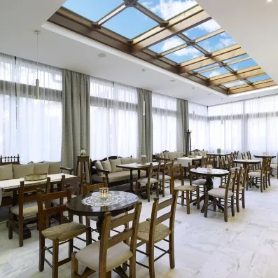 salle de restaurant avec toit vitrée, des chaises en bois et tissus blanc bien décorée